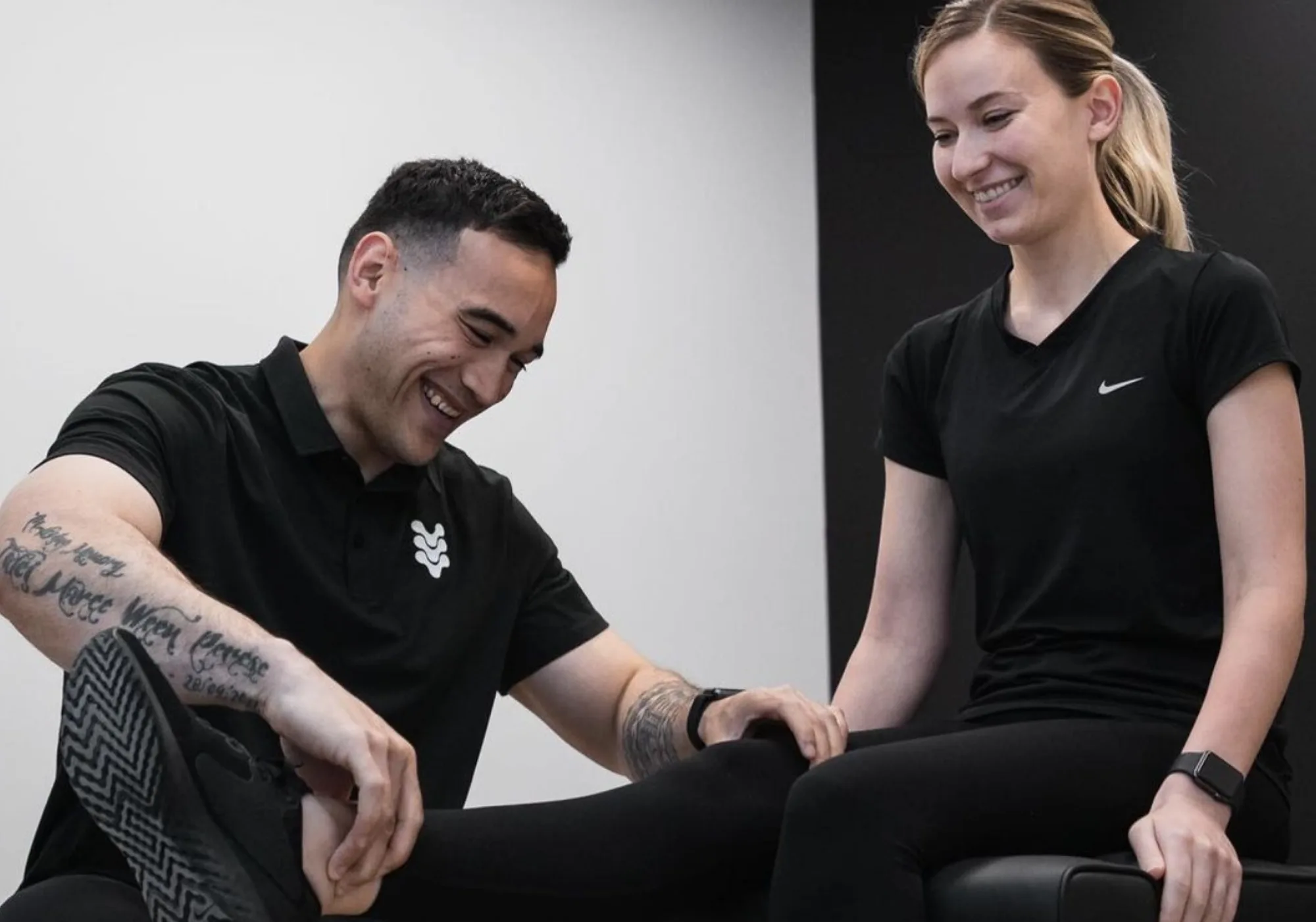 A practitioner at The Spinal Studio assessing a seated client's leg during a workplace injury consultation